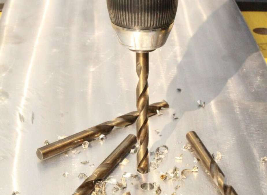 Drill bit boring a hole through a thick slab of metal